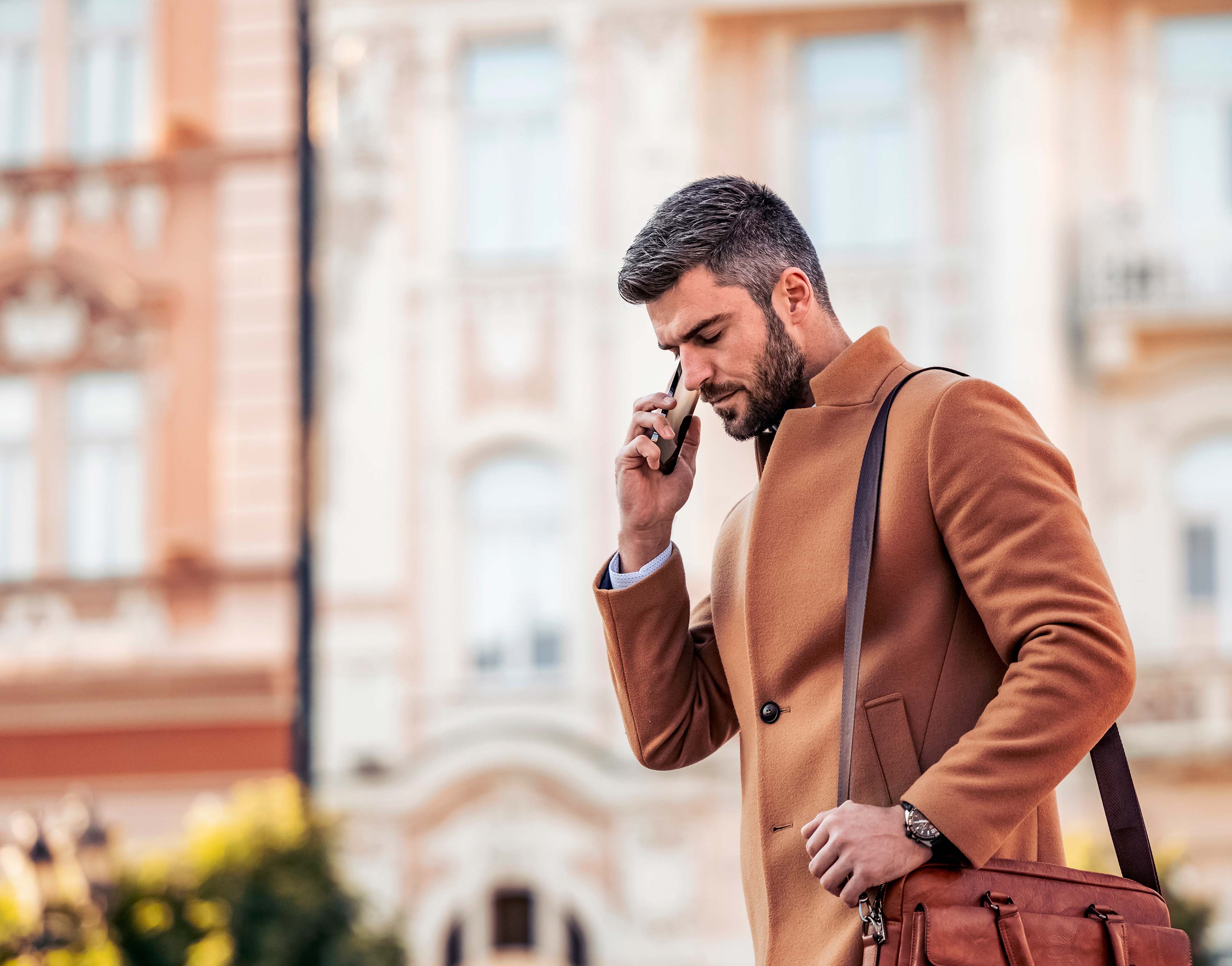 Imagen de un hombre caminando en una ciudad haciendo llamadas de negocios.