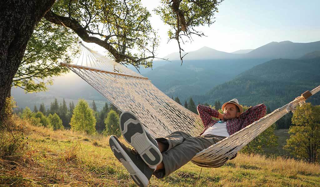 Hombre descansando en hamaca al aire libre al atardecer. Por qué viajar te hace tanto bien