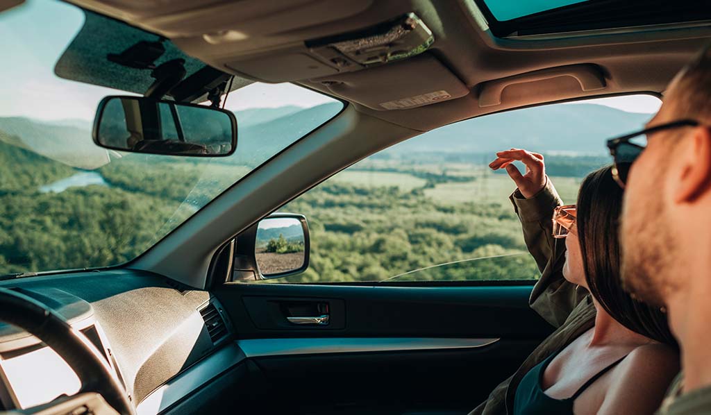 Pareja admirando el paisaje desde su auto