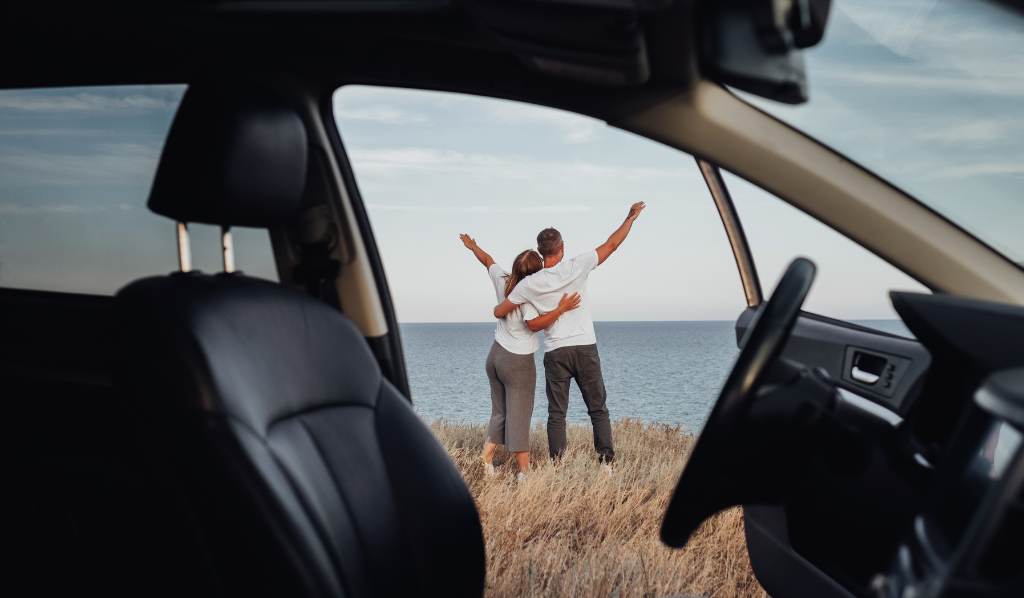 Vista desde el interior del auto, joven pareja en viaje por carretera