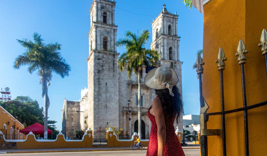 Turista tomando una foto con su teléfono móvil de la catedral de San Servacio durante el día en la ciudad de Valladolid en Yucatán, México. 