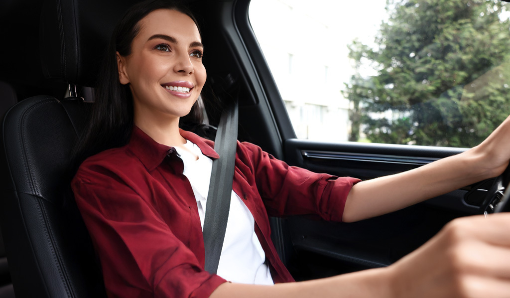 Mujer con el cinturón de seguridad sosteniendo el volante mientras conduce su auto.