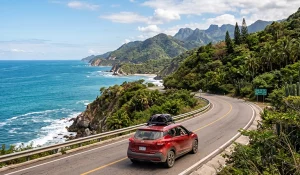 Auto en carretera panorámica  de Puerto Vallarta con el Pacífico a un lado y vegetación de la Sierra Madre al otro, turismo con renta de auto Avis.