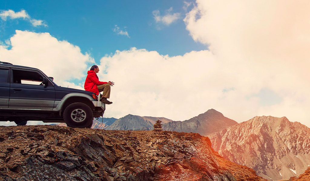 :Feliz Viajero sentado en su auto sobre las montañas. excursión en 4x4