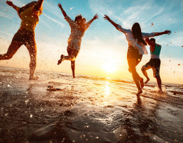 Imagen a contraluz de un atardecer en la playa y unos amigos saltando muy felices
