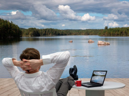 Imagen de un hombre visto de espaldas relajándose en un lago vestido formalmente después de hacer Travel Office