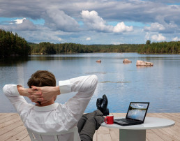 Imagen de un hombre visto de espaldas relajándose en un lago vestido formalmente después de hacer Travel Office