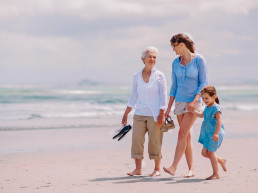 Retrato de una abuela con su hija y nieta disfrutando un soleado día en la playa