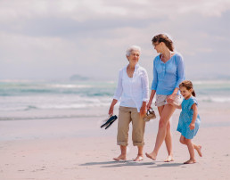 Retrato de una abuela con su hija y nieta disfrutando un soleado día en la playa