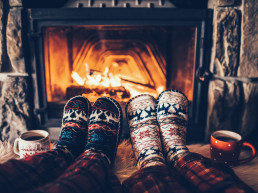 Pies en calcetines de lana cerca de la chimenea de Navidad