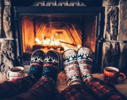 Pies en calcetines de lana cerca de la chimenea de Navidad