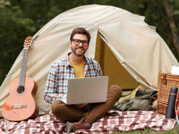 Hombre trabajando con un portátil, un campamento