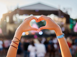 Manos forman el signo del corazón en el festival de música de la playa del atardecer