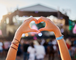Manos forman el signo del corazón en el festival de música de la playa del atardecer