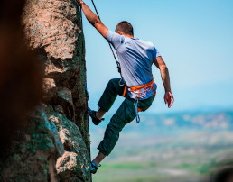 Un escalador de rocas encontrando un punto de apoyo en la empinada montaña que está escalando