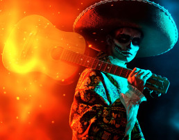 Artista mexicano con traje tradicional y maquillaje de cráneo de azúcar en su cara toca la guitarra en el Día del Carnaval Muerto.