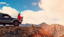 Feliz Viajero sentado en su auto sobre las montañas. excursión en 4x4