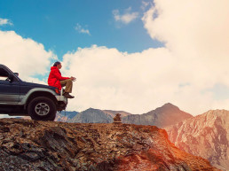 Feliz Viajero sentado en su auto sobre las montañas. excursión en 4x4