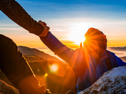 gente del equipo de senderismo ayudándose mutuamente con un amigo ayudándose mientras sube a la roca de montaña