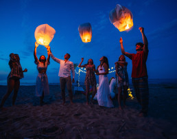 Grupo de amigos prendiendo globos de cantoya en la playa